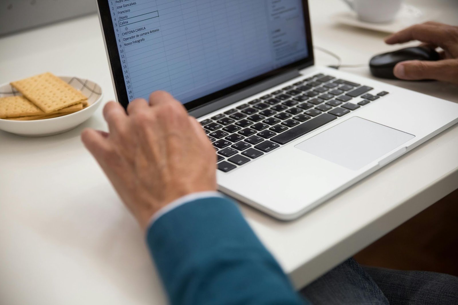 Business professional working on a laptop with a spreadsheet on the screen.