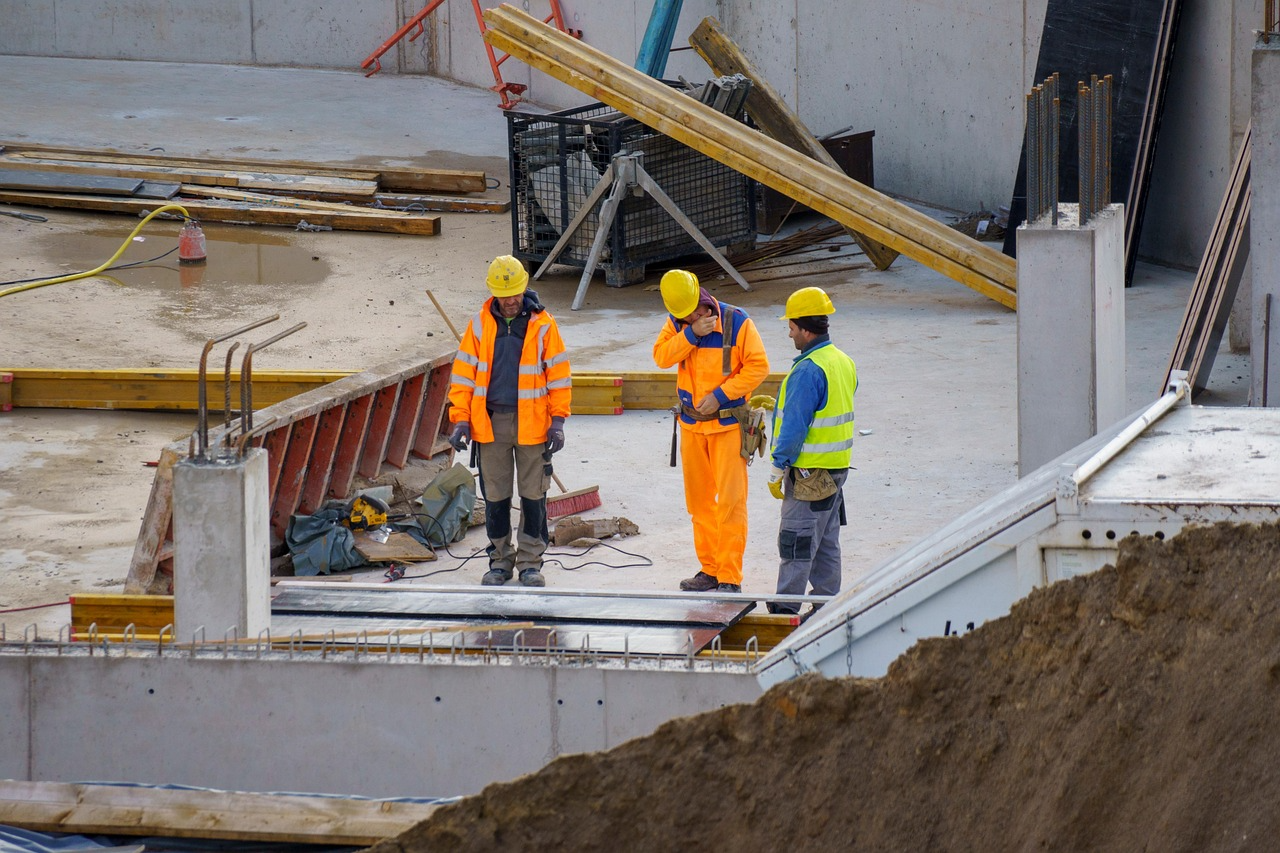 Three engineers in hard hats are discussing on a construction site