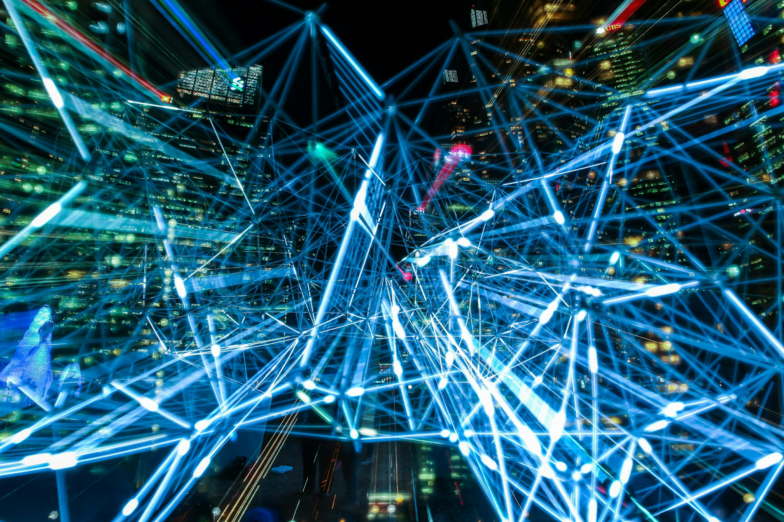 Glowing blue neural network mesh with interconnected nodes overlaid on a nighttime city skyline.